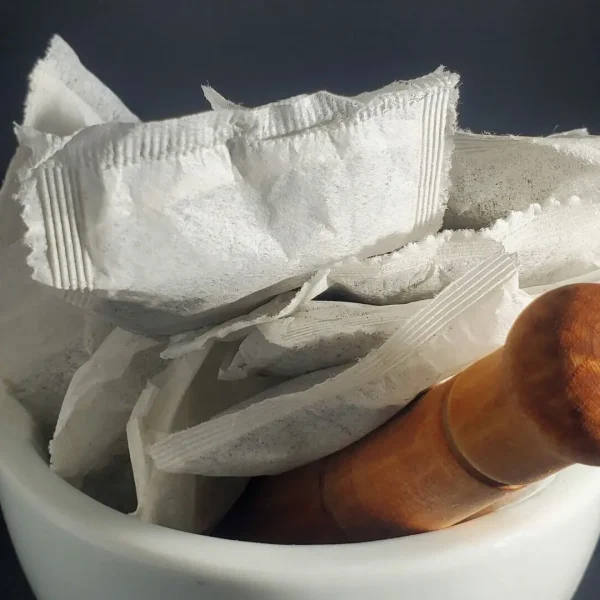 White Maeng Da kratom tea bags arranged in a traditional mortar and pestle, emphasizing the natural and herbal qualities of the product.