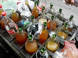 A lineup of assorted glass bottles filled with colorful traditional jamu herbal tonics.